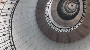 Una escalera de caracol con columna central y barandillas de metal.