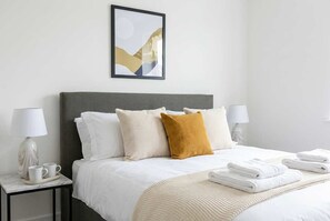 A hotel room with a bed, two bedside tables, a framed picture on the wall, and a window.