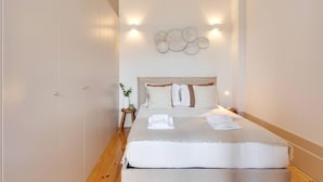 Un dormitorio ordenado con una cama grande, un armario y luces fijadas a la pared.