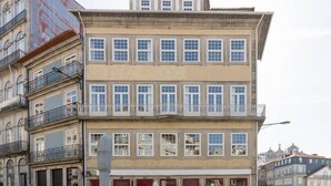 Un edificio a più piani con un ristorante al piano terra, caratterizzato da porte rosse e tavoli all'aperto.