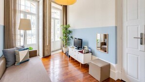 Un soggiorno moderno con un divano, una televisione, una pianta e un'ampia finestra.