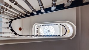 Una escala espiraltra amb baranes metàl·liques i una claraboia central.