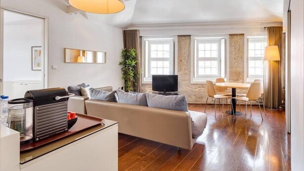 Ein modernes Wohnzimmer mit Sofa, Fernseher und Essbereich.