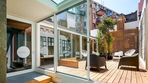 A modern apartment with a glass wall, wooden deck, and outdoor seating area. - The A5 Luxury Studio #1 by DA'HOME (Porto)