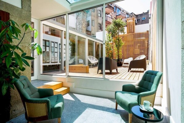 A modern room with large glass windows, a wooden deck, and two green armchairs. - The A5 Luxury Studio #1 by DA'HOME (Porto)