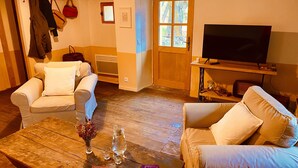 A cozy living room with two sofas, a coffee table with books and a vase, a television on a wooden stand, and a door with a window.