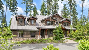 Une cabane en rondins à deux étages, avec des fondations en pierre, de grandes fenêtres et une cheminée en pierre.