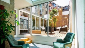 A modern room with large glass windows, a wooden deck, and two green armchairs.