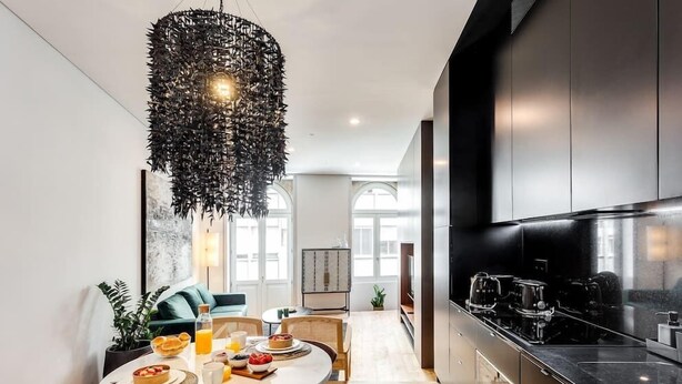 A modern kitchen with a round dining table, a hanging light fixture, and stainless steel appliances.