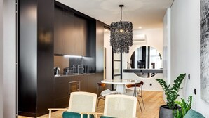 A modern kitchen with dark cabinetry, a round dining table, and a hanging light fixture.