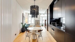 A modern kitchen with a round dining table, pendant lighting, and stainless steel appliances.