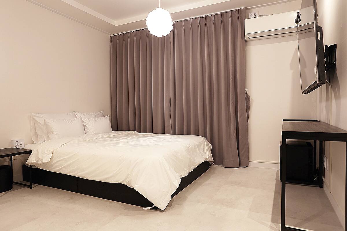 Quarto com cama, escrivaninha e televisão.