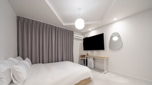 Una habitación de hotel moderna con una cama grande, un escritorio, un televisor de pantalla plana y una lámpara en el techo.