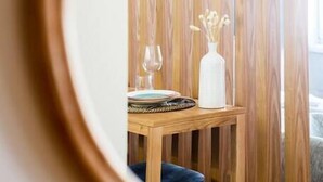 A wooden-framed mirror reflecting a dining area with a table, a vase with dried flowers, and a glass. - Boavista Blue Studio by DA'HOME (Porto)