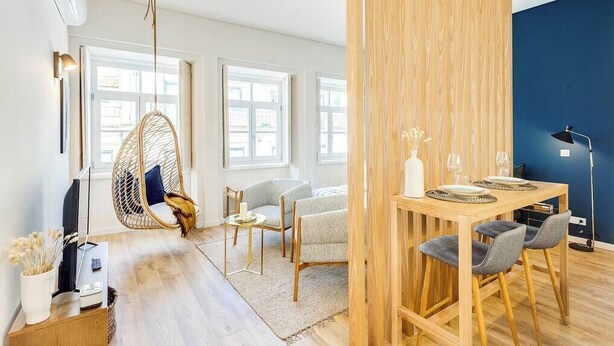 A modern living room with a hanging chair, a dining table with chairs, and a large window. - Boavista Blue Studio by DA'HOME (Porto)