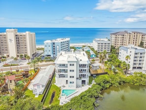 A coastal hotel complex with multiple buildings, a swimming pool, and a view of the ocean.
