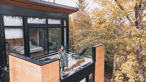 Un bâtiment moderne doté d’un balcon en verre donnant sur une forêt.