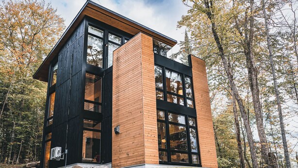 Un bâtiment moderne à deux étages, doté de grandes fenêtres et d’un mélange de lambris en bois foncé et clair.