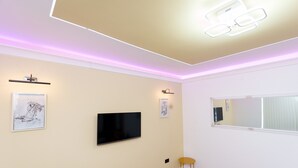 Une pièce dotée d’un téléviseur à écran plat fixé au mur, d’une petite table ronde et d’un miroir également fixé au mur.