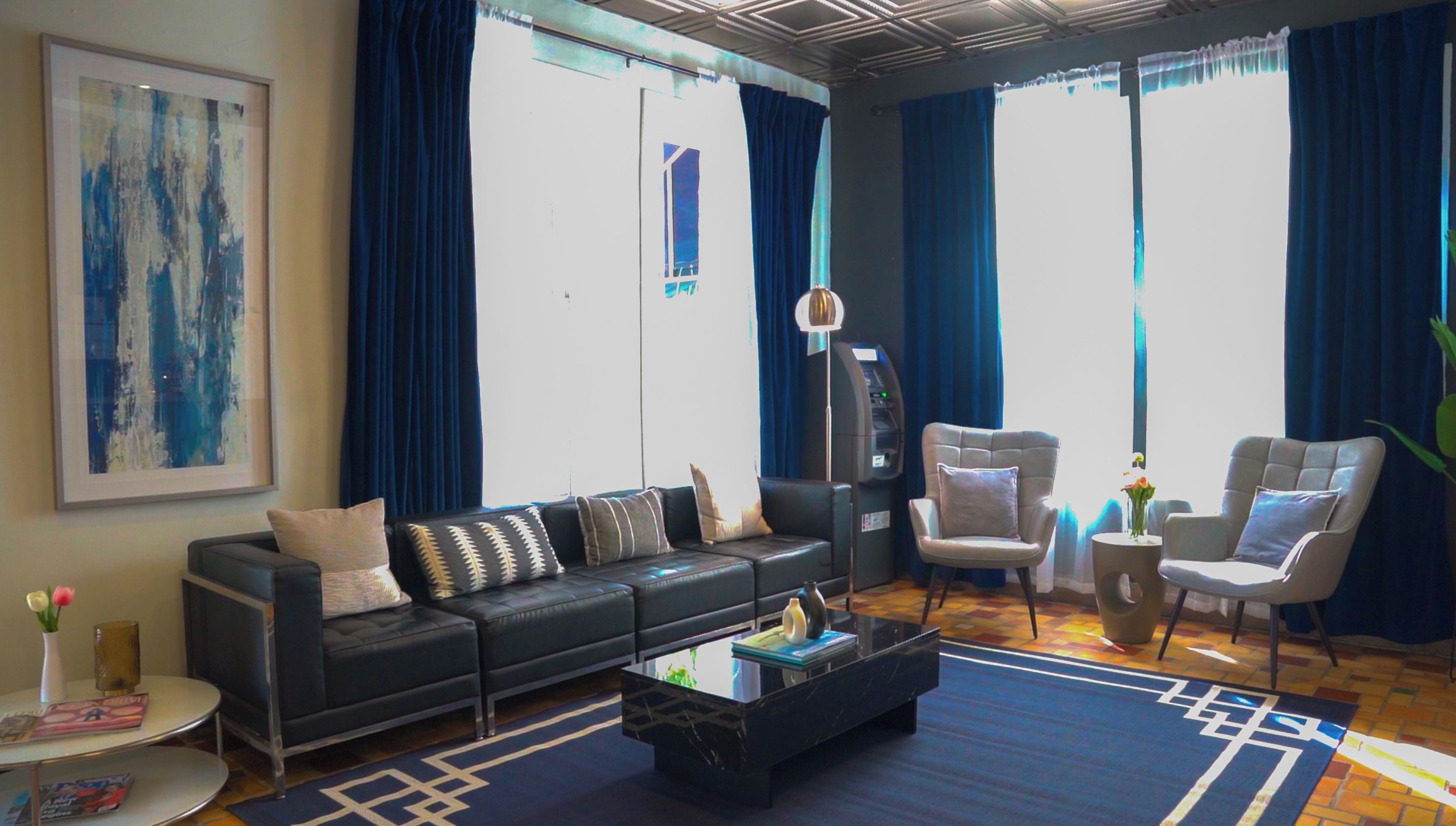 A modern living room with a sofa, armchairs, a coffee table, and a large abstract painting.