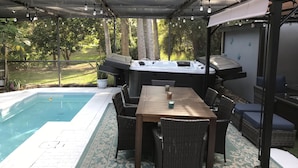 Une terrasse extérieure avec une piscine, un jacuzzi et un espace barbecue.