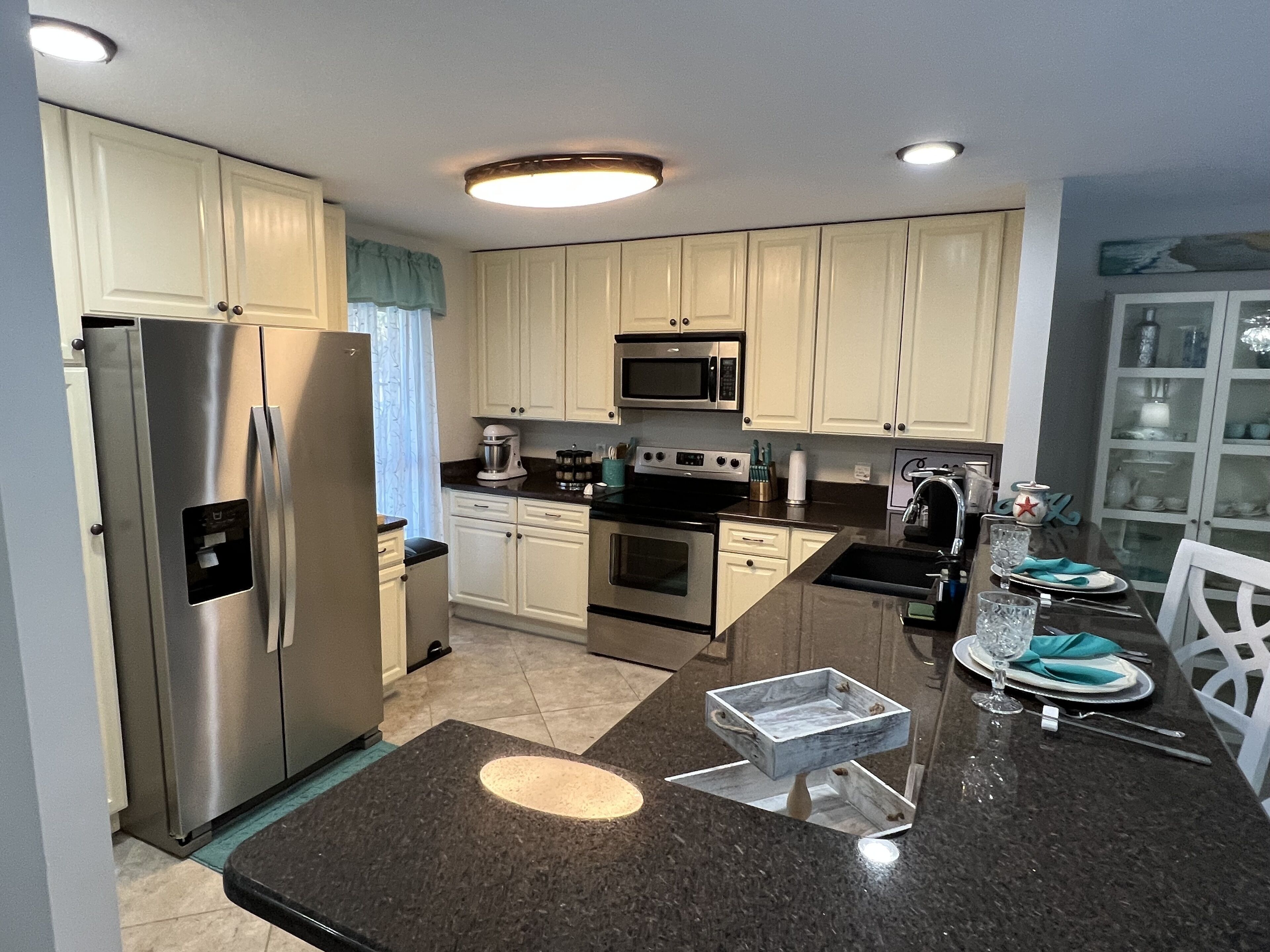 A modern kitchen with stainless steel appliances, white cabinetry, and a dining area with a glass table and chairs.