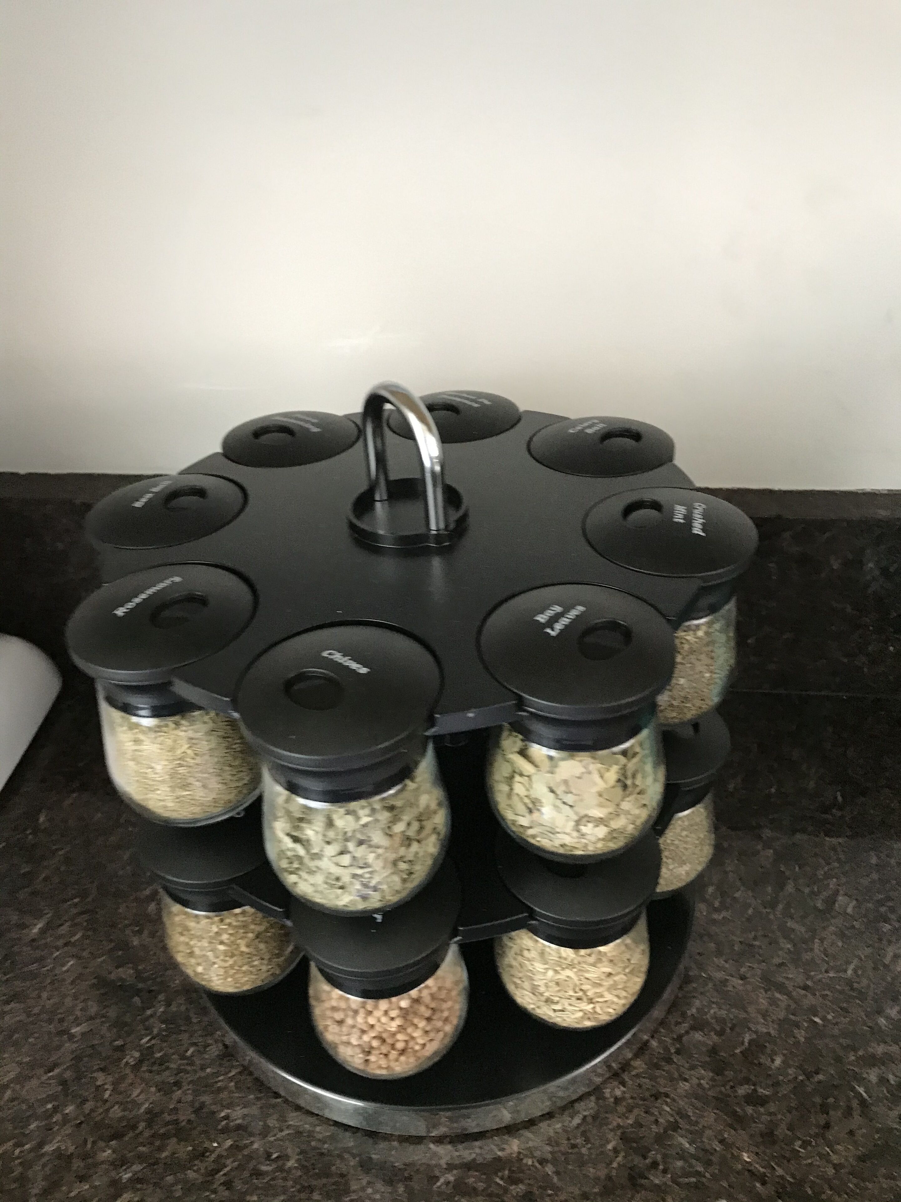 Um porta-temperos com vários recipientes em uma bancada.