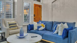 A living room with a blue sofa, a white armchair, and a round coffee table. - Recently renovated Phoenix home with private heated pool and mountian veiws  (Phoenix)