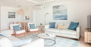 A modern living room with a white sofa, a dining table with chairs, a coffee table, and a TV stand. - Luxury beachfront property sleeps 6 - parking (Salcombe)