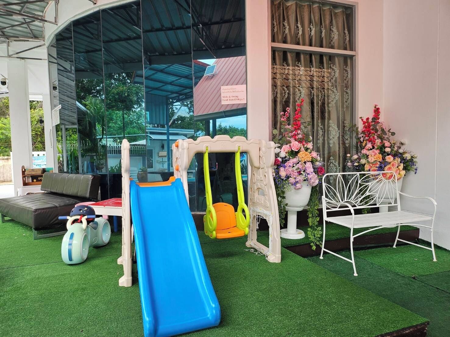 Zona de juegos infantiles con un tobogán, columpios y una silla blanca.