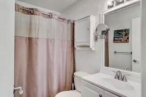 A bathroom with a toilet, sink, and mirror.