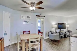 A spacious living room with a dining area, a ceiling fan, a television, and a fireplace.