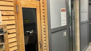 A wooden door leading to a room with a sink and a cabinet. A warning sign is visible on the wall.