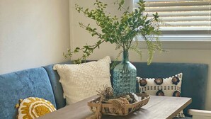 Ein gemütliches Wohnzimmer mit einem blauen Sofa, einem Holztisch und einer Vase mit Grünpflanzen.