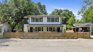 A two-story house with a front porch and a fenced driveway. - Steps From Park Circle | Mavis at the Quad (North Charleston)