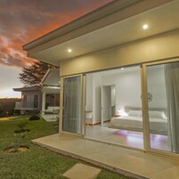 Una casa moderna con un dormitorio con paredes de vidrio, un balcón y vistas del paisaje.