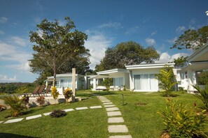 A modern resort with a well-maintained lawn, a stone pathway, and a pool area with lounge chairs. - Adeluna Luxury Ocean View Villas (Cóbano)