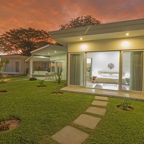 A modern house with a spacious patio, a well-maintained lawn, and a clear view of the interior through large glass doors. - Adeluna Luxury Ocean View Villas (Cóbano)