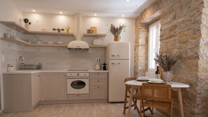A modern kitchen with wooden cabinets, a built-in oven, a white refrigerator, and a dining area with a table and chairs.