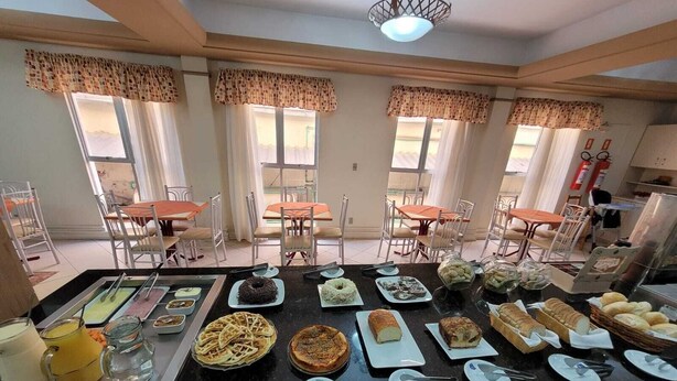 A buffet with various dishes and a seating area with tables and chairs.