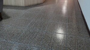 A long, narrow hallway with a reception desk on the left, tiled flooring, and a clock on the wall.