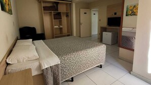 A bedroom with a bed, a desk, a wardrobe, a television, and a bathroom.