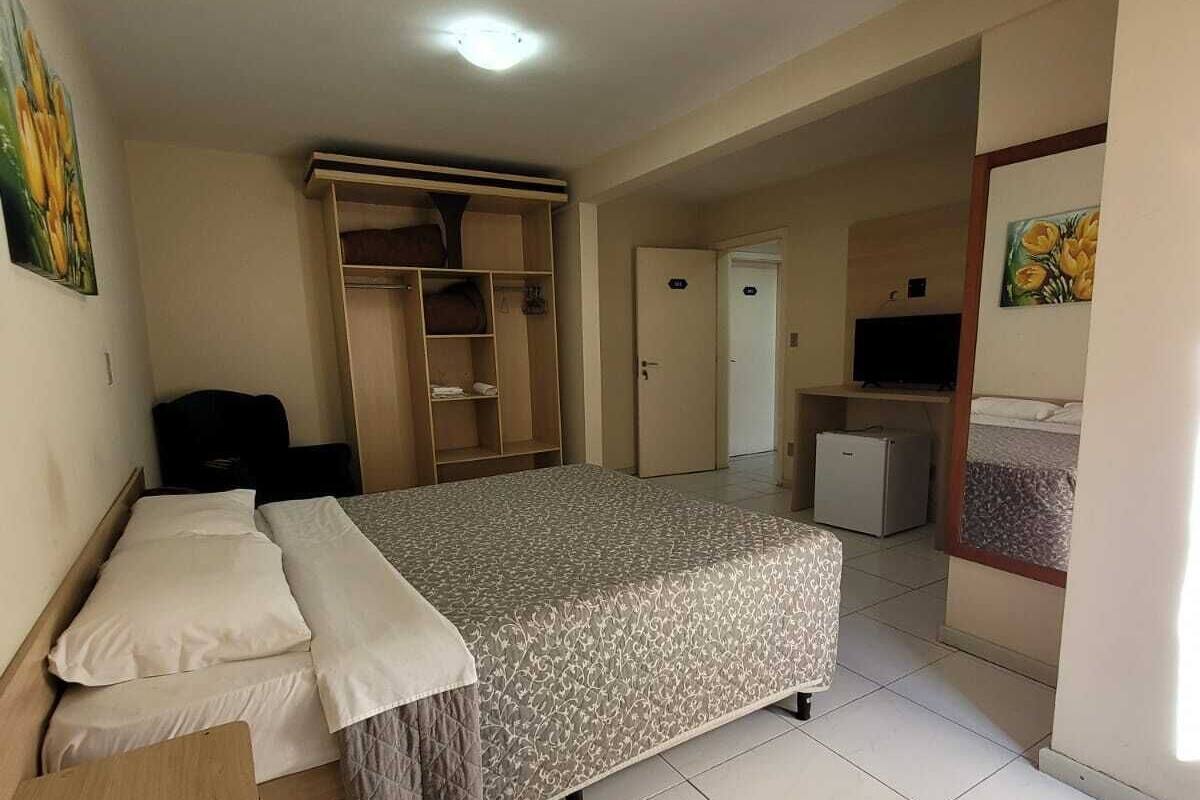 A bedroom with a bed, a desk, a wardrobe, a television, and a bathroom.