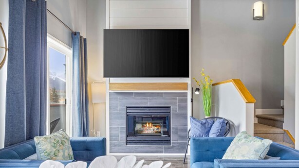 Un salon moderne avec une cheminée, des canapés bleus et un téléviseur à écran plat.