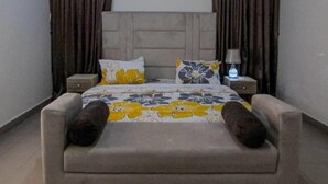 A bedroom with a bed, two nightstands, a lamp, and curtains.