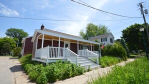 A two-story house with a porch and steps leading to the front door. - Boyne Bungalow (Boyne City)