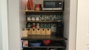 Une cuisine compacte équipée d’un four à micro-ondes, d’une machine à café et de placards de rangement.