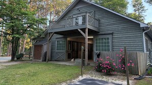 Une maison en bois à deux étages, dotée d’un balcon, d’un garage et d’un porche à l’avant.