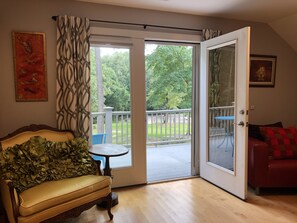 A living room with a sofa, a table, and a sliding glass door leading to a balcony. - Peaceful Horse Farm Retreat — private balcony and pasture views! (Vass)