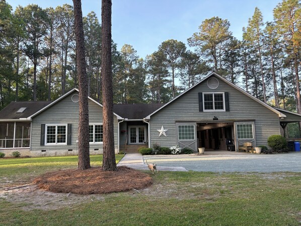 A two-story house with a garage, a star decoration on the front, and a dog in the driveway. - Peaceful Horse Farm Retreat — private balcony and pasture views! (Vass)